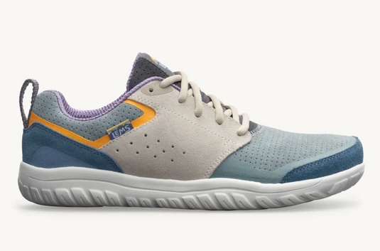 A low-top athletic shoe shown in profile against a light off-white background. The shoe features a light gray suede upper, a dusty blue perforated toe and heel, a white sole, an orange accent stripe, and a purple collar lining.